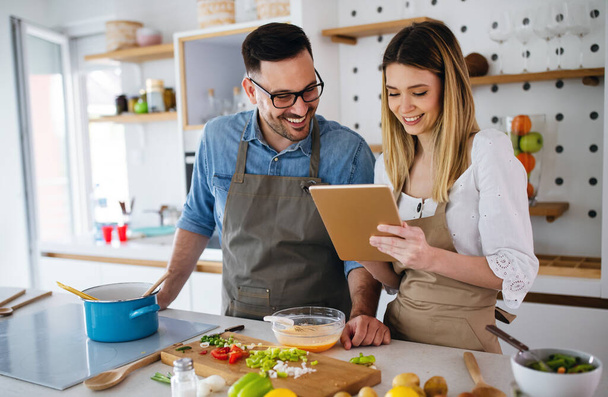 Happy couple enjoys and having fun preparing healthy meal together at home kitchen. - 写真・画像