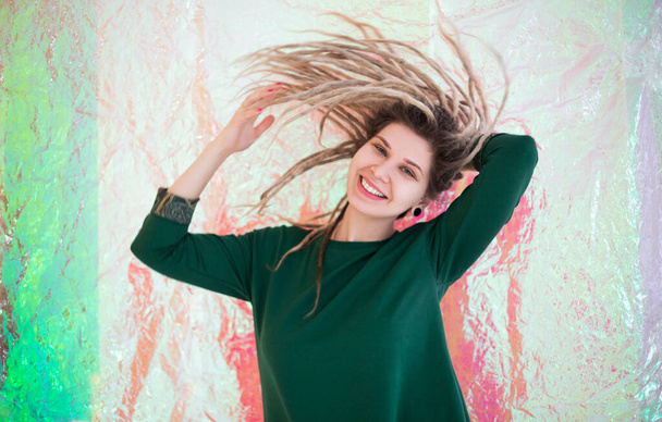 Весела молода жінка в барвистому вбранні дивиться на камеру з посмішкою і трясе дредлоки ізольовані на білому тлі
 - Фото, зображення