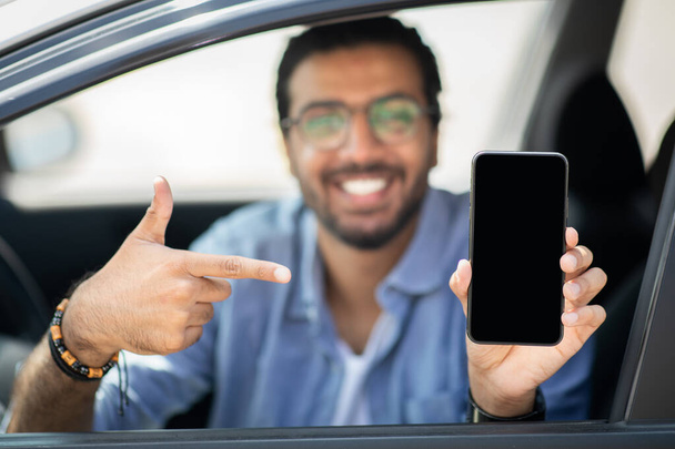Šťastný indián řidič drží smartphone s prázdnou obrazovkou, mockup - Fotografie, Obrázek