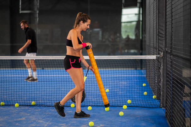 Chica recoge padle o pelotas de tenis en el centro de la cancha - Foto, Imagen