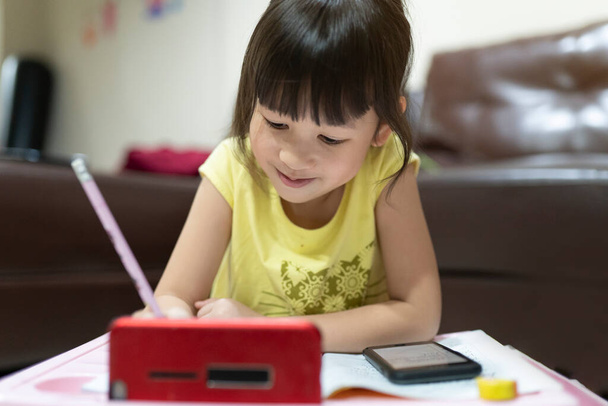 Cute Asian girl using smartphone to study online with teacher on video call at home. homeschooling, distance learning. quarantine concept. online education. - Photo, Image