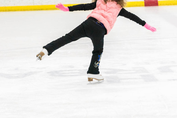 Menina praticando patinação artística se move na pista de gelo interior. - Foto, Imagem