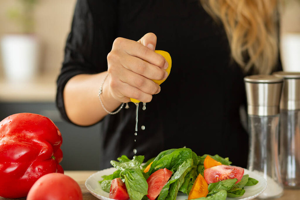 PREPARING SALAD IN THE KITCHEN, hands squeeze lemon, tomatoes, kitchen, avocado - Фото, изображение