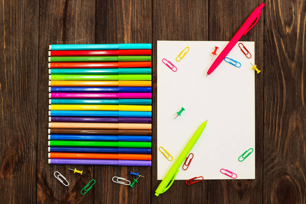Scuola creativa flatley. Su un tavolo di legno ci sono pennarelli multicolori e un foglio con spazio vuoto per il testo. - Foto, immagini