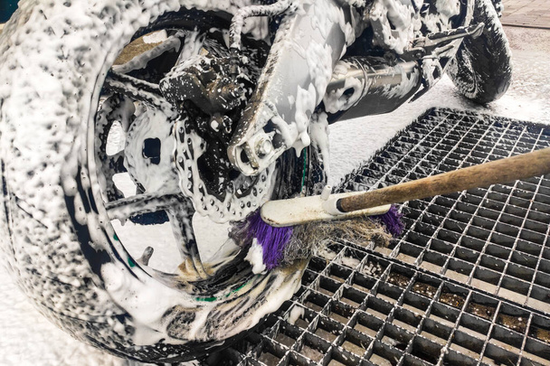 Motorrad in der Waschanlage. Das Rad mit Schaum von Schmutz reinigen. - Foto, Bild