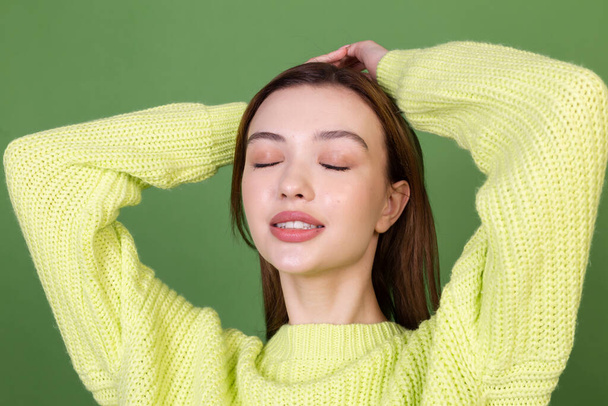 Jeune femme avec une peau naturelle parfaite propre et maquillage grandes lèvres brunes sur fond vert heureux positif souriant posant mobile - Photo, image