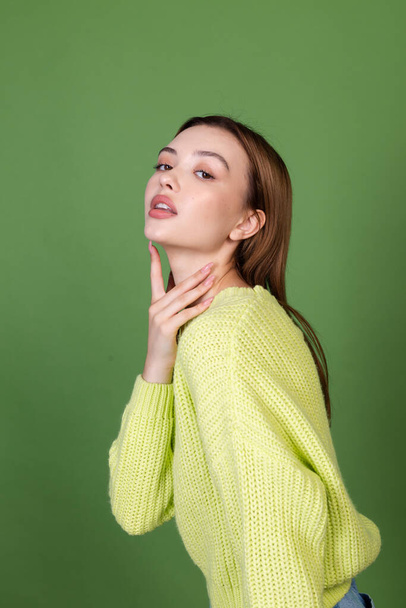 Young woman with clean perfect natural skin and makeup brown big lips on green background posing  - Foto, imagen