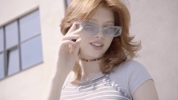 vista basso angolo di rossa adolescente ragazza regolazione occhiali da sole  - Filmati, video