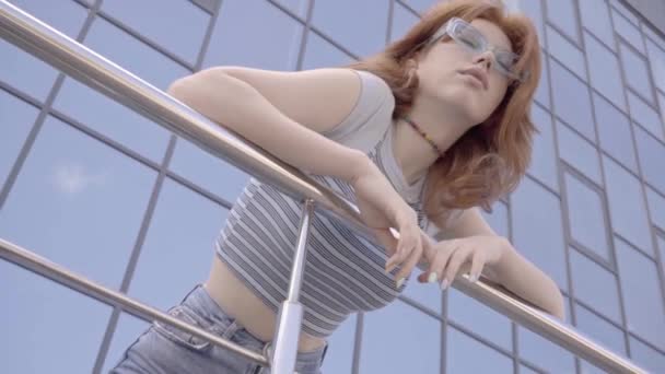low angle view of teenage girl in sunglasses leaning on handrail - Кадри, відео