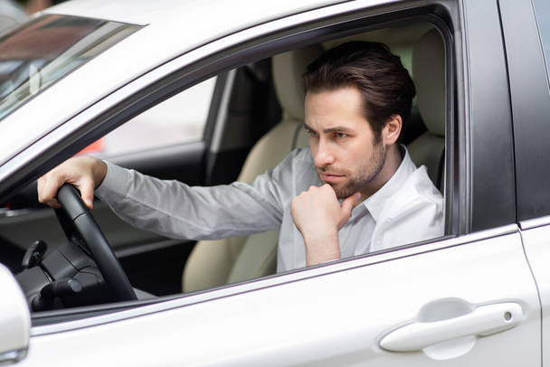 Раздраженный уставший молодой человек за рулем машины. Бизнесмен опаздывает на встречу - Фото, изображение