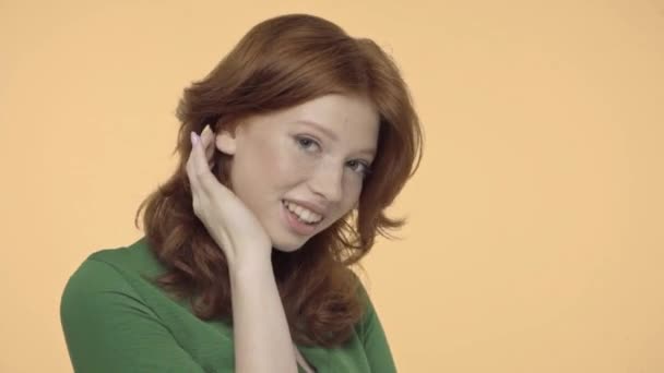 flirty ragazza adolescente regolazione capelli rossi isolati su giallo - Filmati, video