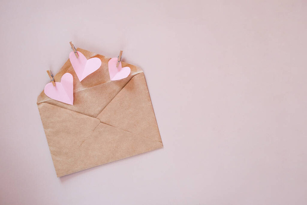 Creative minimal Valentine's Day concept. Envelope, valentines, white and pink heart confetti on a pastel pink background. Flat lay, top view, copy space - Foto, Imagen
