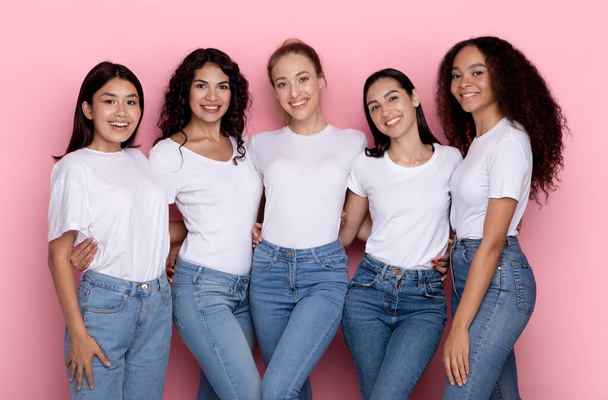 Gruppo di cinque felici signore multirazziali che si abbracciano su sfondo rosa - Foto, immagini