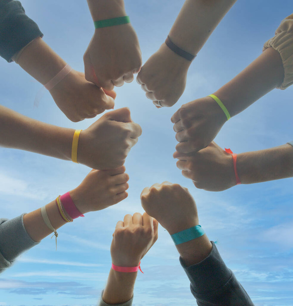 arms with colored cloth bracelets on the wrists and with closed fists during a camp or excursion to differentiate the teams to play concept of union strength and fellowship - Photo, Image
