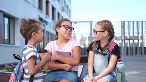  Três crianças com mochila sentar e conversar juntos  - Filmagem, Vídeo