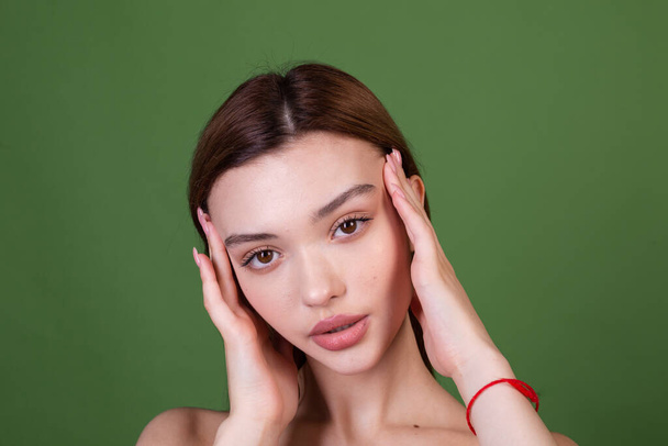 Jeune femme avec maquillage naturel parfait grandes lèvres brunes en robe rouge à pois sur fond vert avec épaules nues, concept de visage de beauté - Photo, image