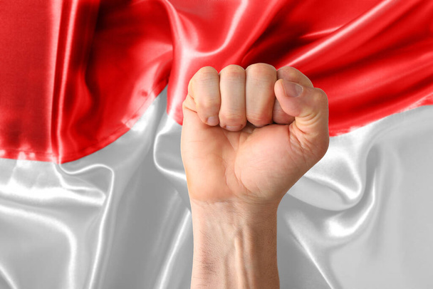 Mano con pugno stretto contro bandiera indonesiana - Foto, immagini