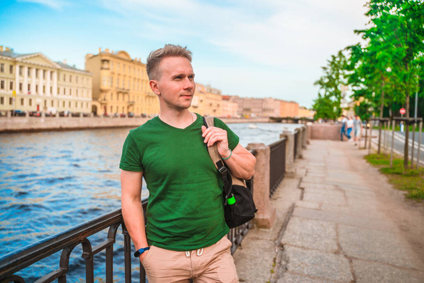 A young man walks along the embankment in the center of St. Petersburg in the summer - Φωτογραφία, εικόνα
