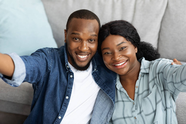 Retrato de feliz joven afroamericano pareja tomando selfie juntos en casa - Foto, Imagen