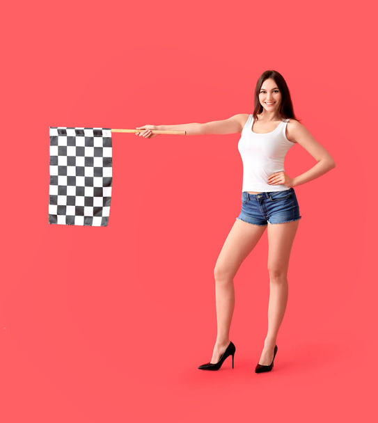 Beautiful young woman with racing flag on color background - Photo, Image