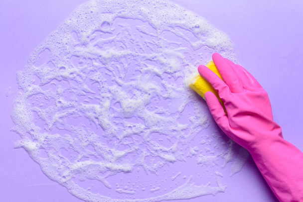 Woman with sponge cleaning color surface - Photo, Image