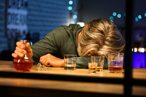 夜遅く家で酒のボトルと無意識の酔った男 - 写真・画像