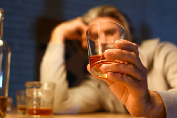Старший мужчина с бокалом выпивки поздно вечером дома, крупным планом - Фото, изображение