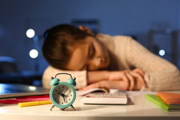 Alarm clock on table of tired little girl at home late in evening - Photo, Image