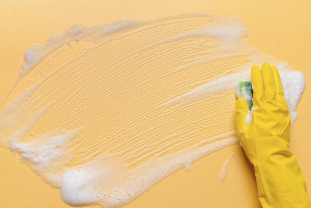 Mujer con esponja limpieza superficie de color - Foto, Imagen