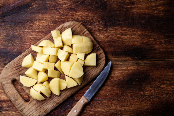 Sliced raw potatoes on a wooden background. Preparation for cooking. - Foto, immagini