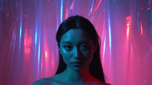 bonita asiático jovem mulher olhando para câmera no néon rosa e azul  - Filmagem, Vídeo