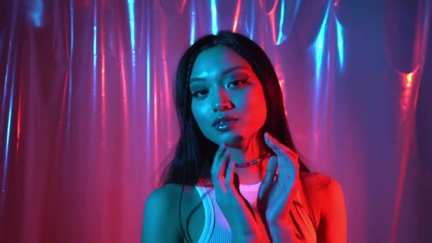 bonita asiático jovem mulher com brilhante pele posando no néon rosa e azul  - Filmagem, Vídeo