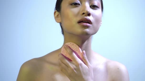 aziatische vrouw schrobben hals met puimsteen op blauw - Video