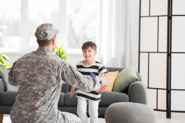Un niño pequeño conociendo a su padre militar en casa. Celebración del Día de Memorial - Foto, imagen