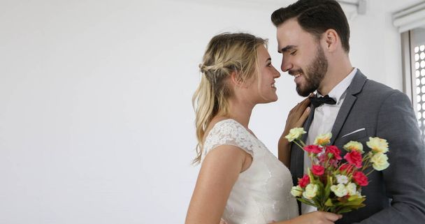 Les amants donnent des fleurs à la mariée et embrassé heureux et couple amour debout dans studio de mariage - Photo, image