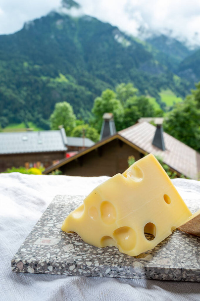 Cheese collection, French cow cheese emmental and french mountains village in Haute-Savoie in summer on background - Photo, Image
