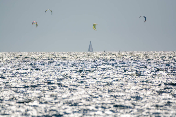 2021 год. Экстрим водные виды спорта - винтовая фольга, кайт-серфинг, виндсерфинг, ветреный день на пляже Альманарре недалеко от Тулона, юг Франции - Фото, изображение