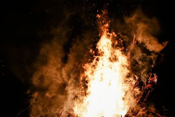 美しい火花と黒の背景と地面に赤い炎の薪で火災. - 写真・画像