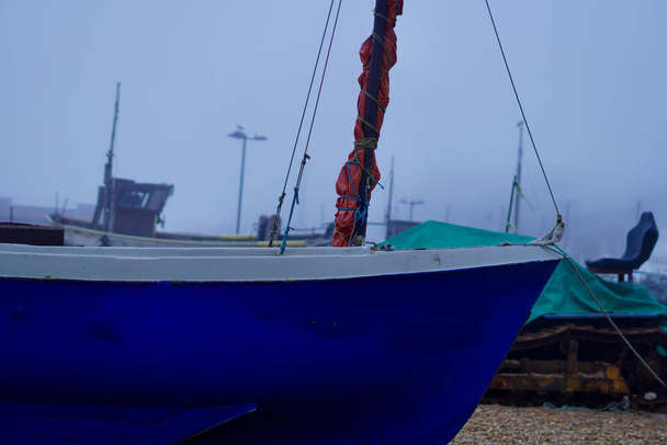 Hastingsissa on sumuinen, sumuinen päivä ja veneet ovat merisumun peitossa, kun ne makaavat vyöryvällä rannalla odottamassa seuraavaa nousuvettä..  - Valokuva, kuva