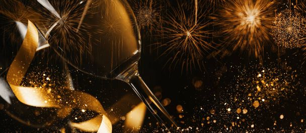 Altın kurdeleli ve altın parıltılı iki şampanya bardağı koyu arkaplanda sıçrıyor. Lüks restoran yemeği kutlaması. Şık bir Noel ve yeni yıl panoramik tasarım pankartı. - Fotoğraf, Görsel