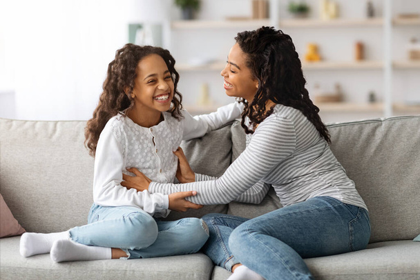 Vrolijke zwarte moeder en dochter hebben plezier samen thuis - Foto, afbeelding