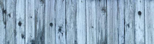 Old bluish wooden wall made of cracked vertical boards partly with knotholes in panoramic close-up - Photo, image
