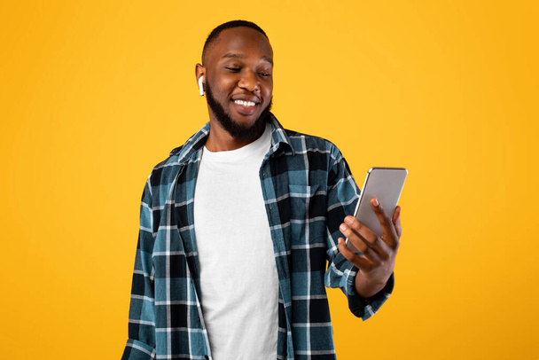 Afričan poslech hudby v aplikaci na Smartphone, žluté pozadí - Fotografie, Obrázek
