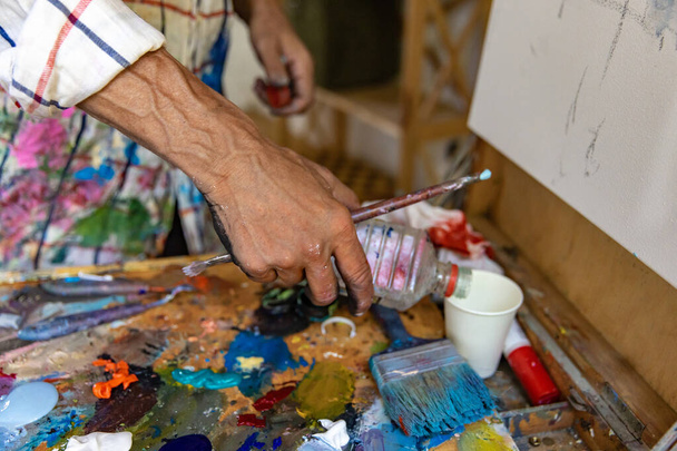 Closeup of hand mixing paint on palette at workshop - Φωτογραφία, εικόνα