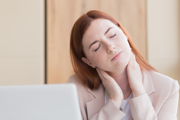 Close-up photo of a red haired business woman with a severe toothache and a headache at the computer, overwork, stress and depression - Photo, image