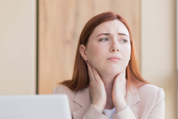 Close-up photo of a red haired business woman with a severe toothache and a headache at the computer, overwork, stress and depression - Foto, Bild