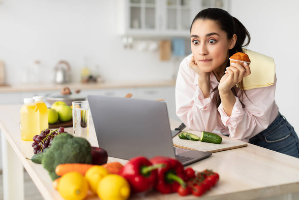 Yllättynyt hämmästynyt nainen katsomassa elokuvaa kannettavan tietokoneen ja syöminen - Valokuva, kuva