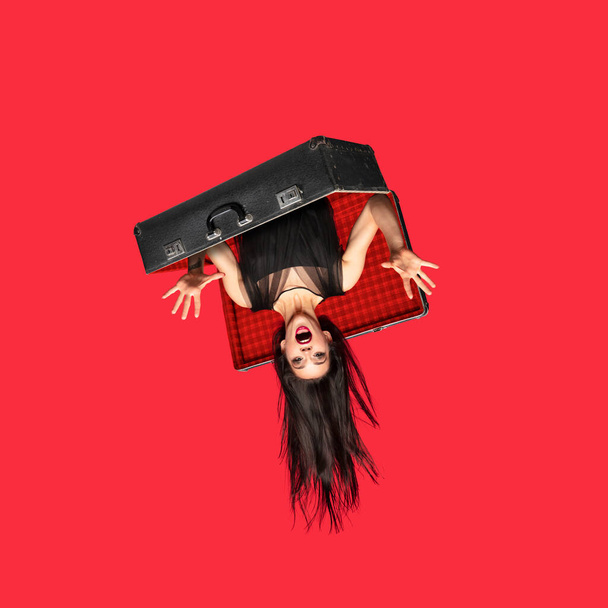 Young woman a witch shouting in retro suitcase isolated on red background. Contemporary art collage - Фото, изображение