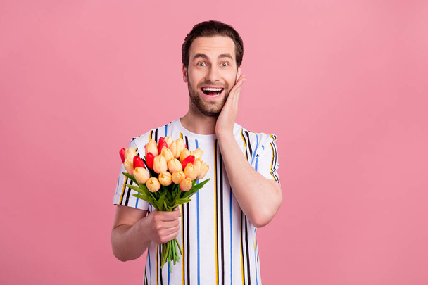 Kuva nuori viehättävä onnellinen positiivinen mies hämmästynyt pidä käsi poski kukkia eristetty vaaleanpunainen väri tausta - Valokuva, kuva