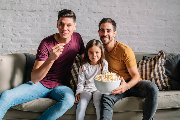 Two parents and their daughter watching a movie together at home. - Foto, immagini